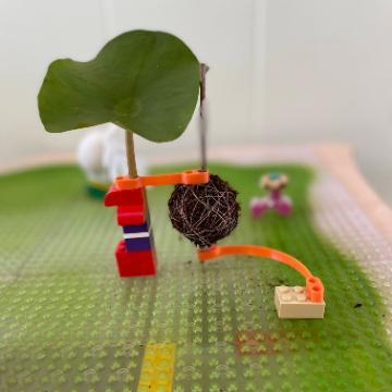 LEGO structures built with plant materials, including a green leaf.