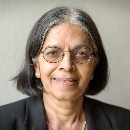 A person smiling wearing glasses and a dark blazer.