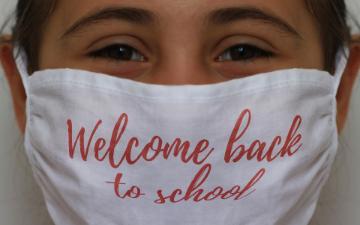 teacher wearing face mask imprinted with the words 