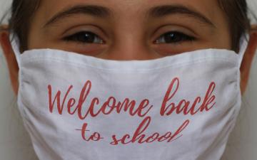 teacher wearing face mask imprinted with the words 