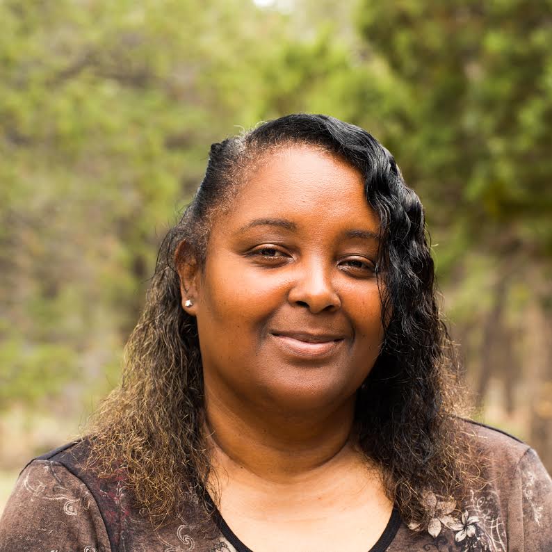 A woman smiling outdoors with trees in the background. image link to story