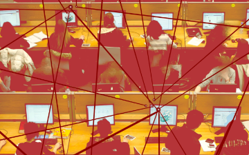 A computer lab with three rows of four desks, each occupied by students working at computers 
