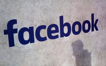 Facebook logo on a wall with a shadow.