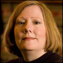 A person looking at the camera in front of bookshelves. image link to story