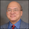 A smiling person wearing glasses, a suit, and a striped tie. image link to story