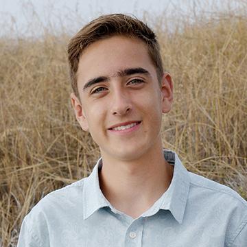 Man in blue shirt outdoors smiling