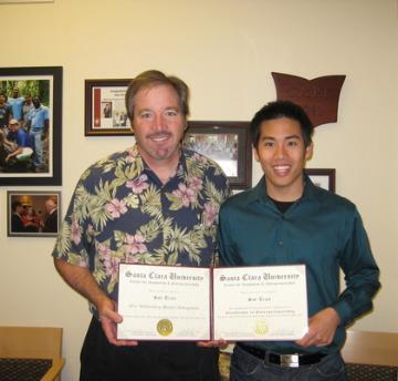 Two people holding a certificate titled 2011 Outstanding Student Entrepreneur in a room.