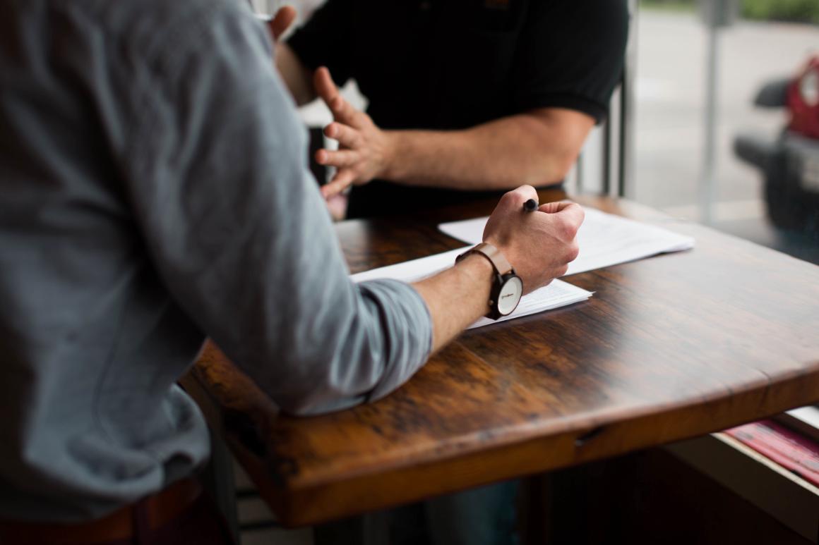 Two people discussing licenses over legal papers.