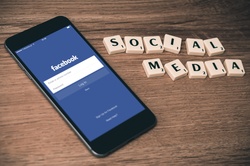 Phone displaying social media login screen and Scrabble tiles spelling 'Social Media Guidelines'.