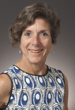 Woman in blue and white patterned dress smiling, titled Angela Robbiano - HOF Committee.