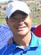 A smiling person in a blue polo and white cap.