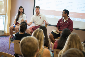Three people discussing campus opportunities in front of an audience.