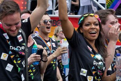 People celebrating in a crowd, some raising their hands and smiling with cameras.