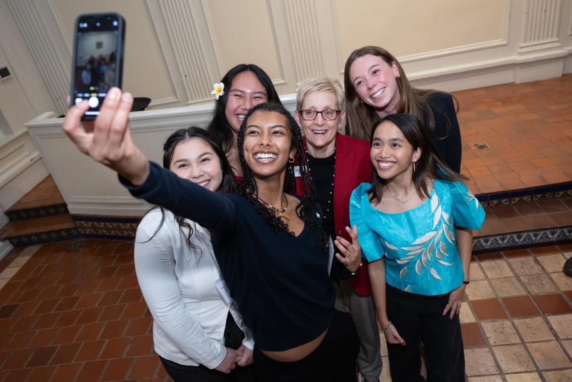 A group of smiling SCU students taking a selfie with SCUs President.