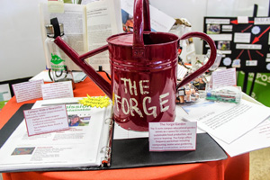 A red watering can with the text Smile, it's spring on a table with various items. image link to story