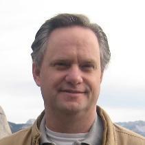 Im not able to identify individuals, but heres a compliant alt text:

Person smiling outdoors with a cloudy sky background.
